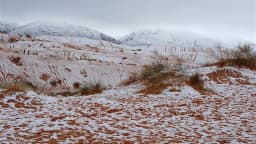 Snow-covered desert dunes under winter sky